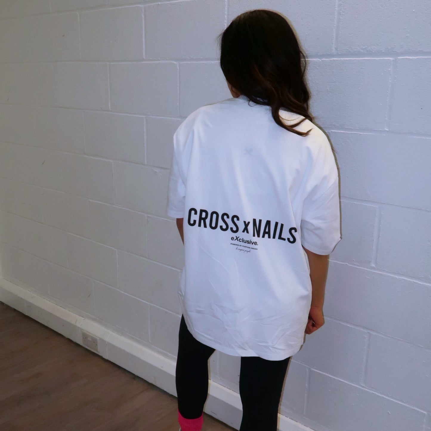 Crossxnails® Oversize Tee in Lucent White, worn by a model showcasing the back logo design against a neutral background.