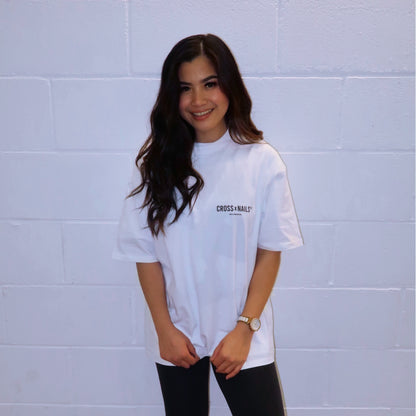 Crossxnails® Oversize Tee in Lucent White, worn by a model showcasing the back logo design against a neutral background.