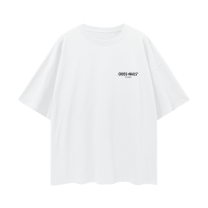 Front view of a Crossxnails® Weargood oversized white T-shirt with a small logo on the chest, unisex design, made from 100% cotton, featuring a loose fit and drop shoulder sleeves